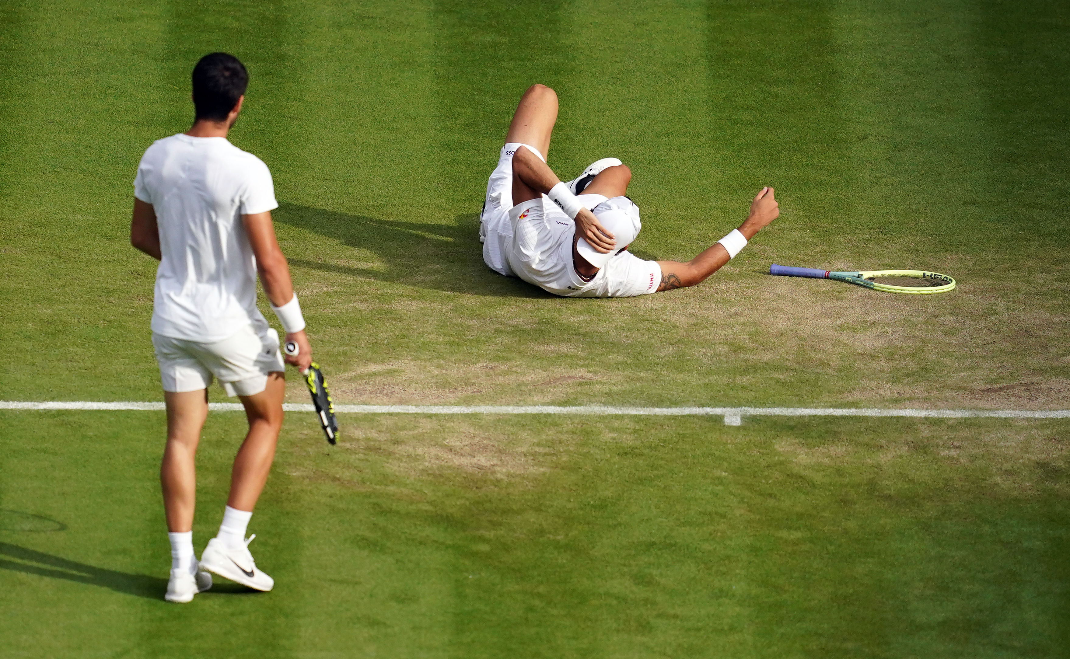 Carlos Alcaraz, left, walks to check on Matteo Berrettini after a slip