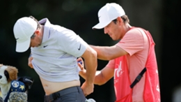 Rory McIlroy, left, has pain-relieving balm applied to his back by his caddie Harry Diamond during the first round of the Tour Championship golf tournament in Atlanta (Alex Slitz/ AP)