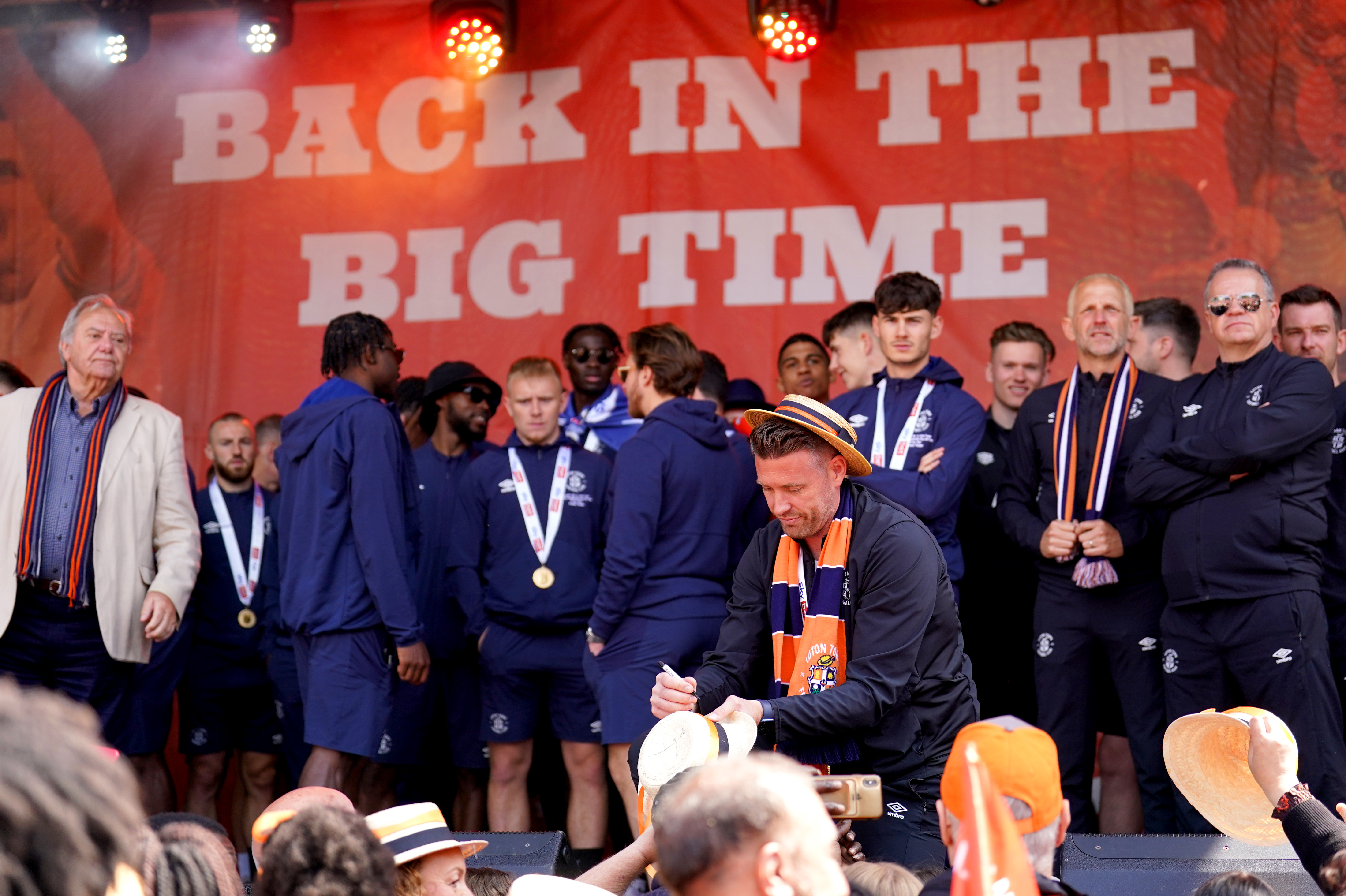 Manager Rob Edwards signs a fan's hat during Luton's 'Back in the Big Time' promotion celebration