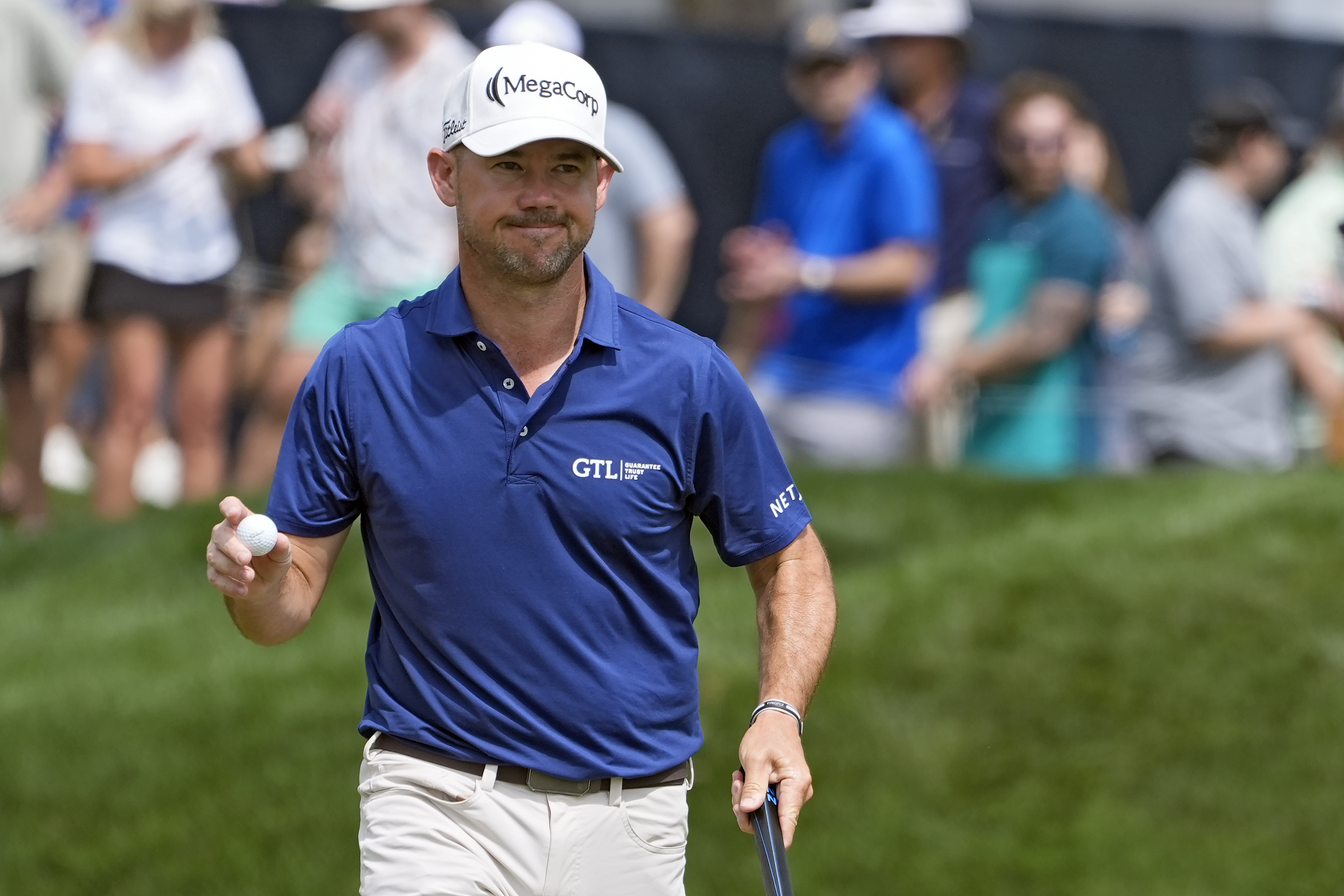 Brian Harman holds up his golf ball