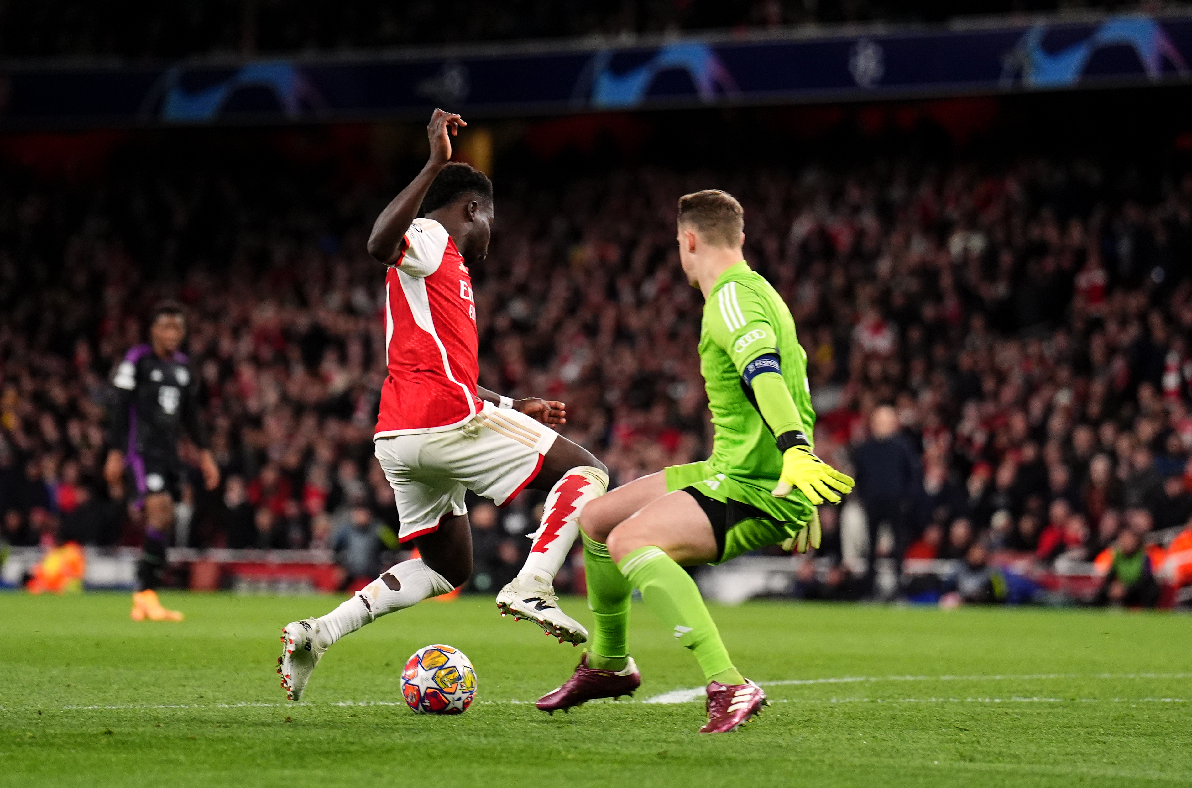 Bukayo Saka, left, goes down under the challenge of Manuel Neuer