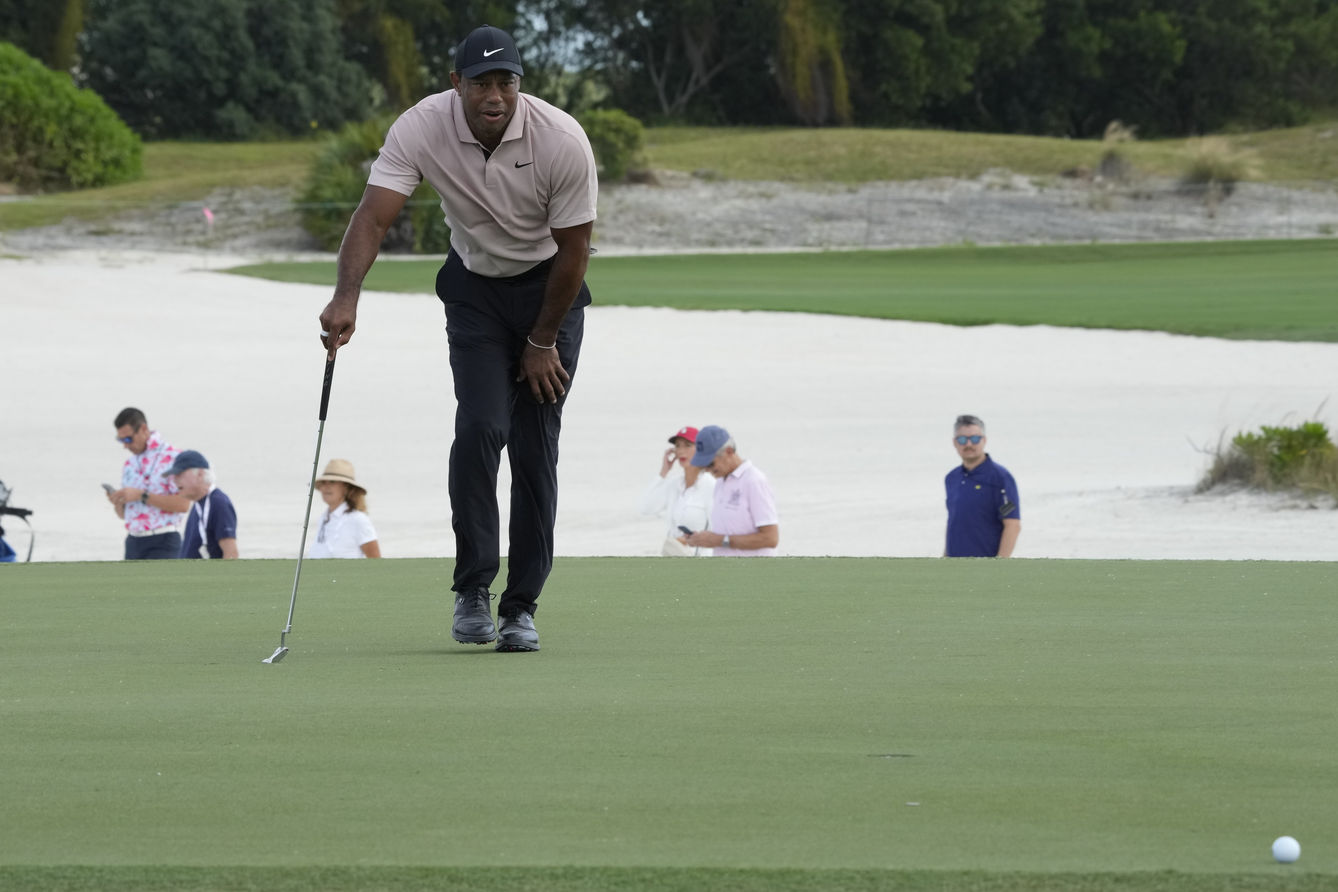 Tiger Woods studies his putt at the third green