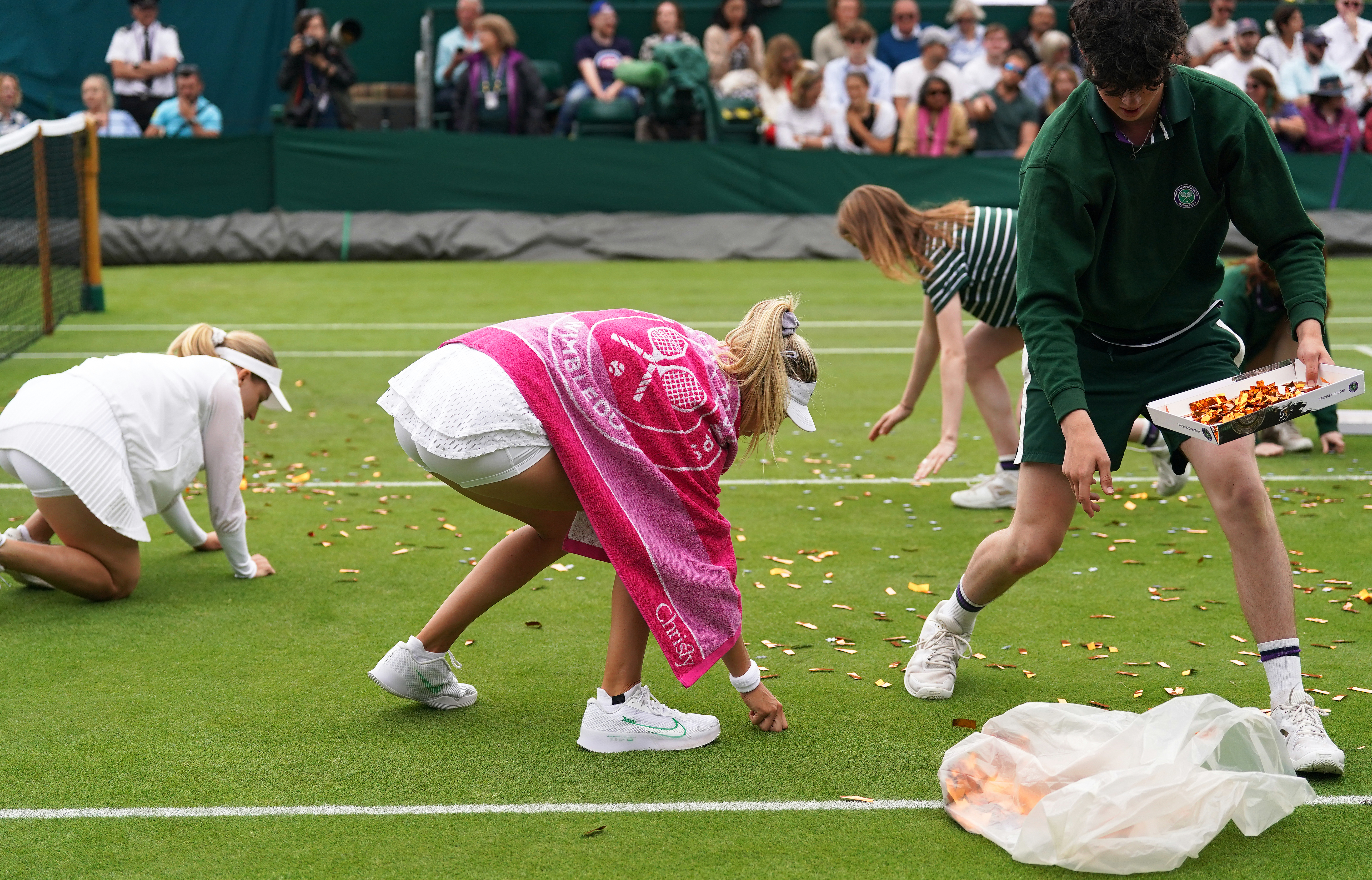 Katie Boulter helps ground staff clear confetti from the court