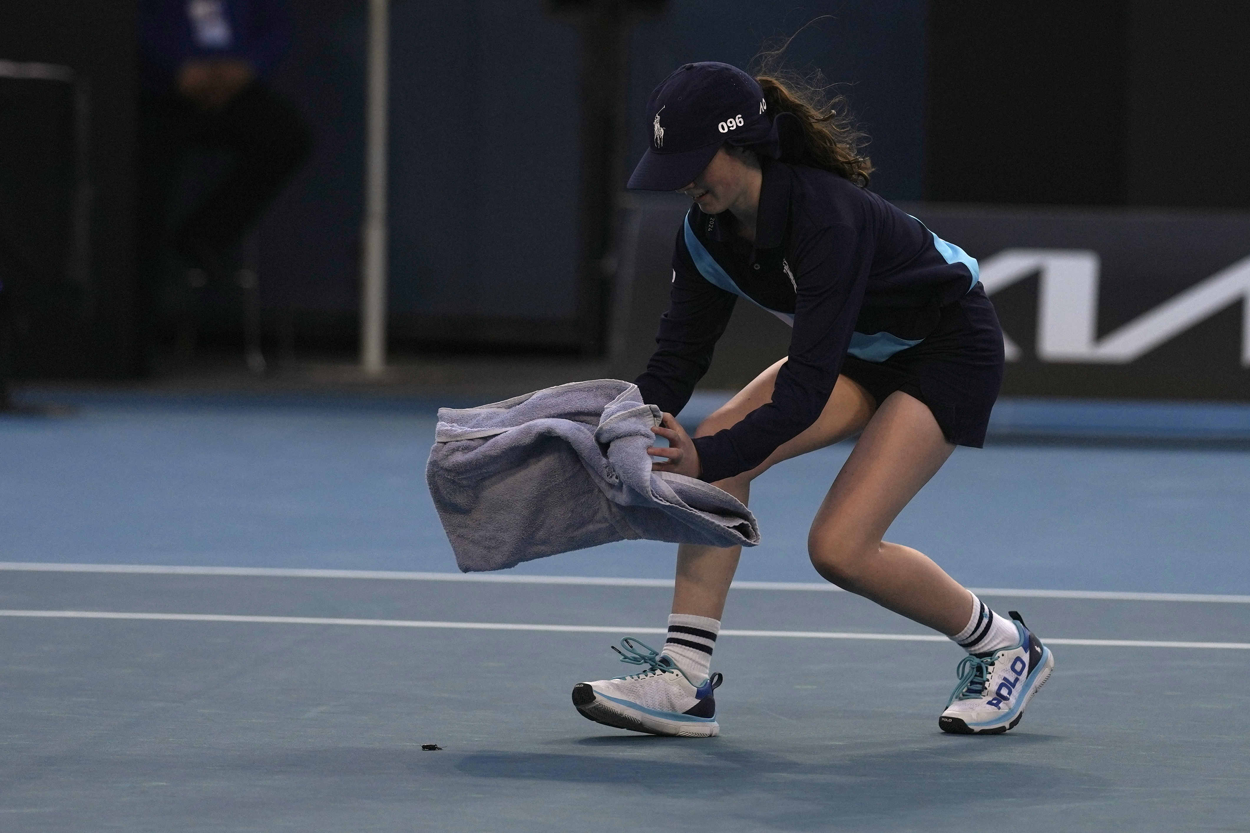 A ball girl tries to catch a bug