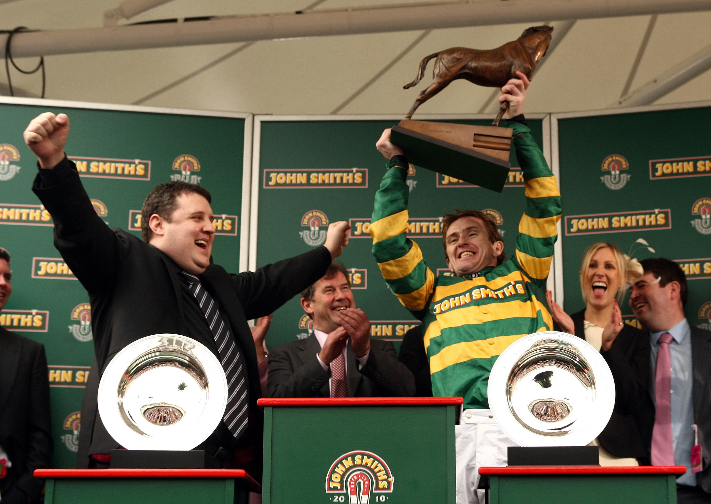 Peter Kay presents AP McCoy (right) with the trophy after winning the Grand National on Don’t Push It as JP McManus looks on