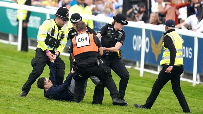 A protester is escorted off the track by police and stewards at Epsom (Mike Egerton/PA)