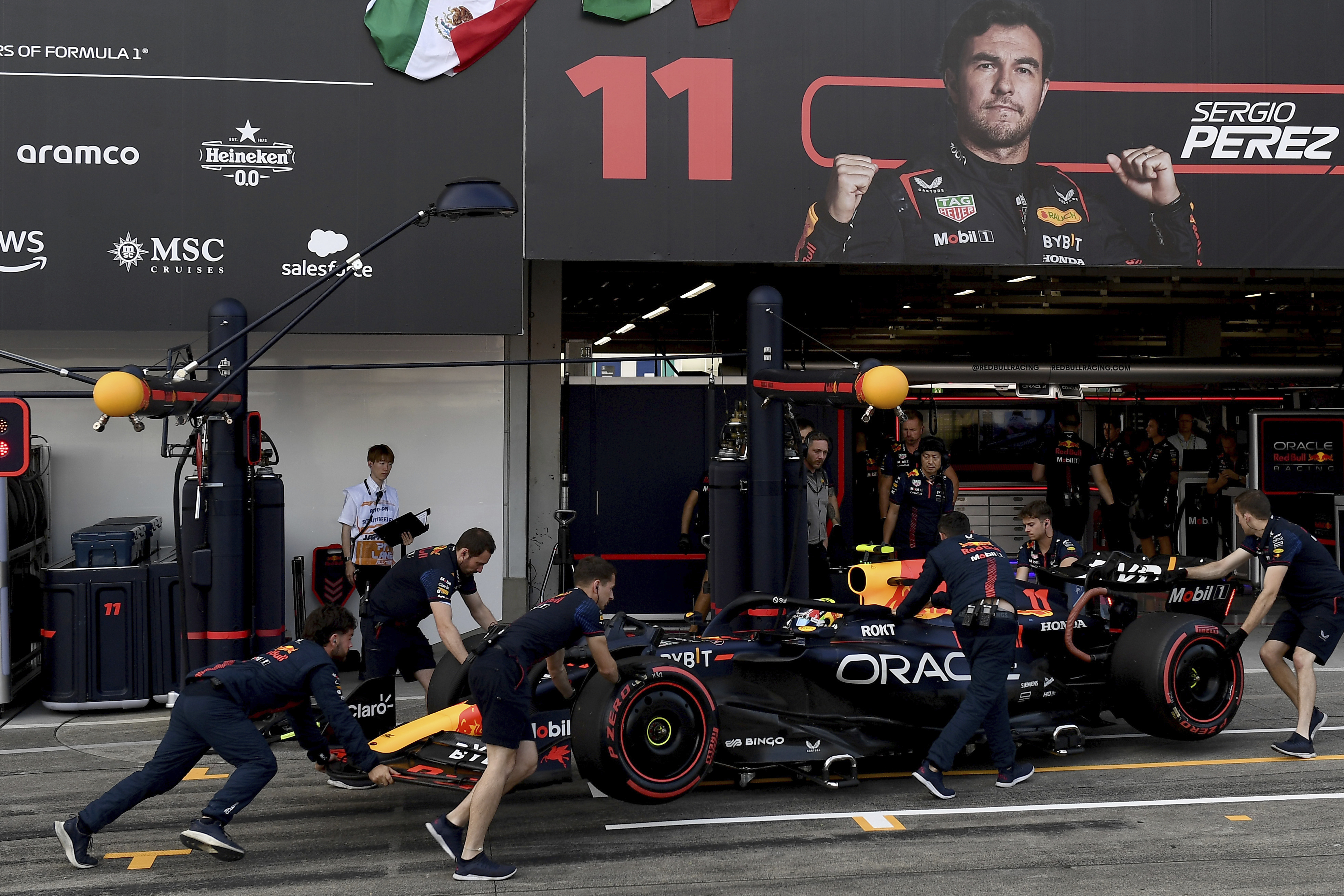 Red Bull mechanics push Sergio Perez's car back into the garage