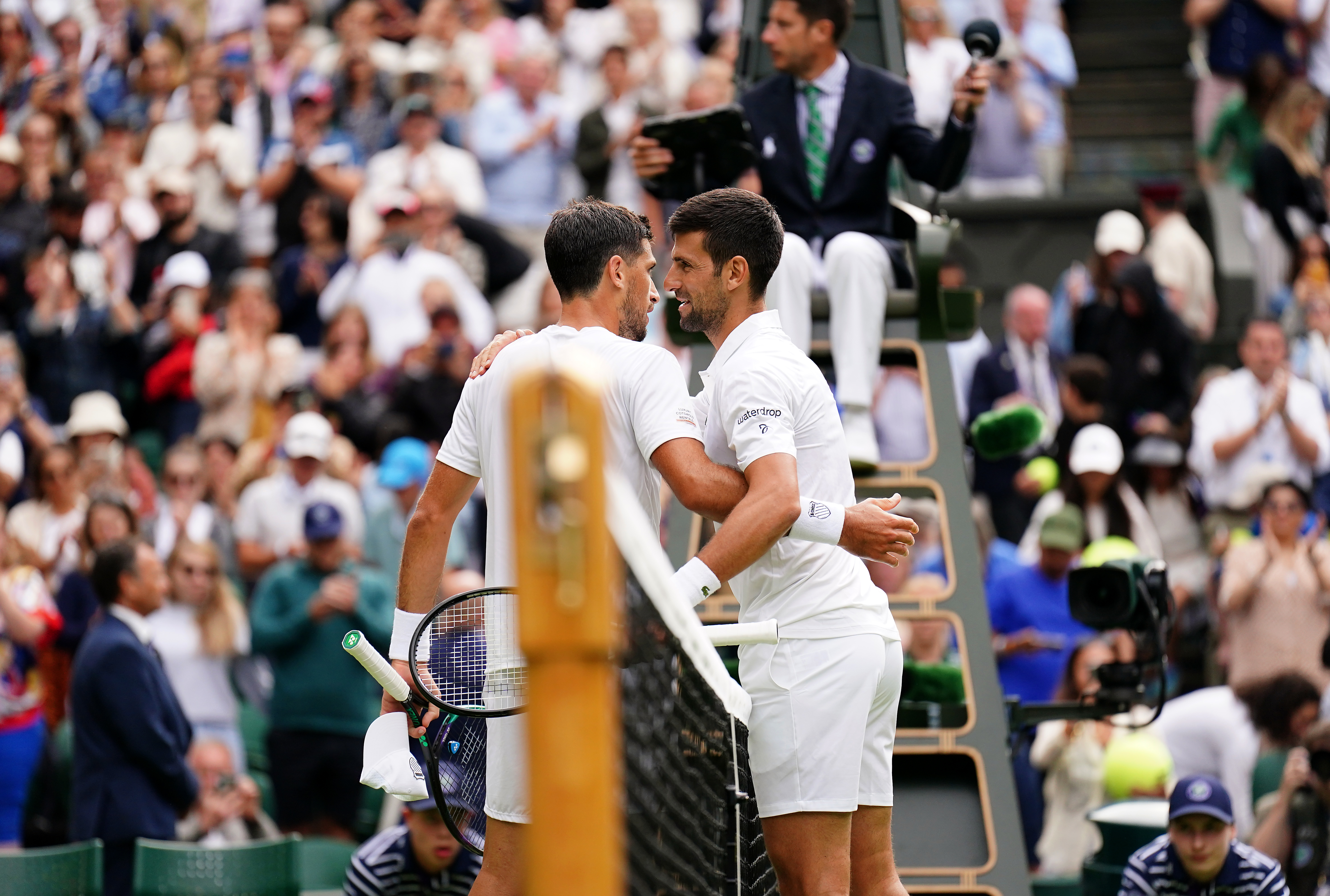 Novak Djokovic and Pedro Cachin embrace at the net