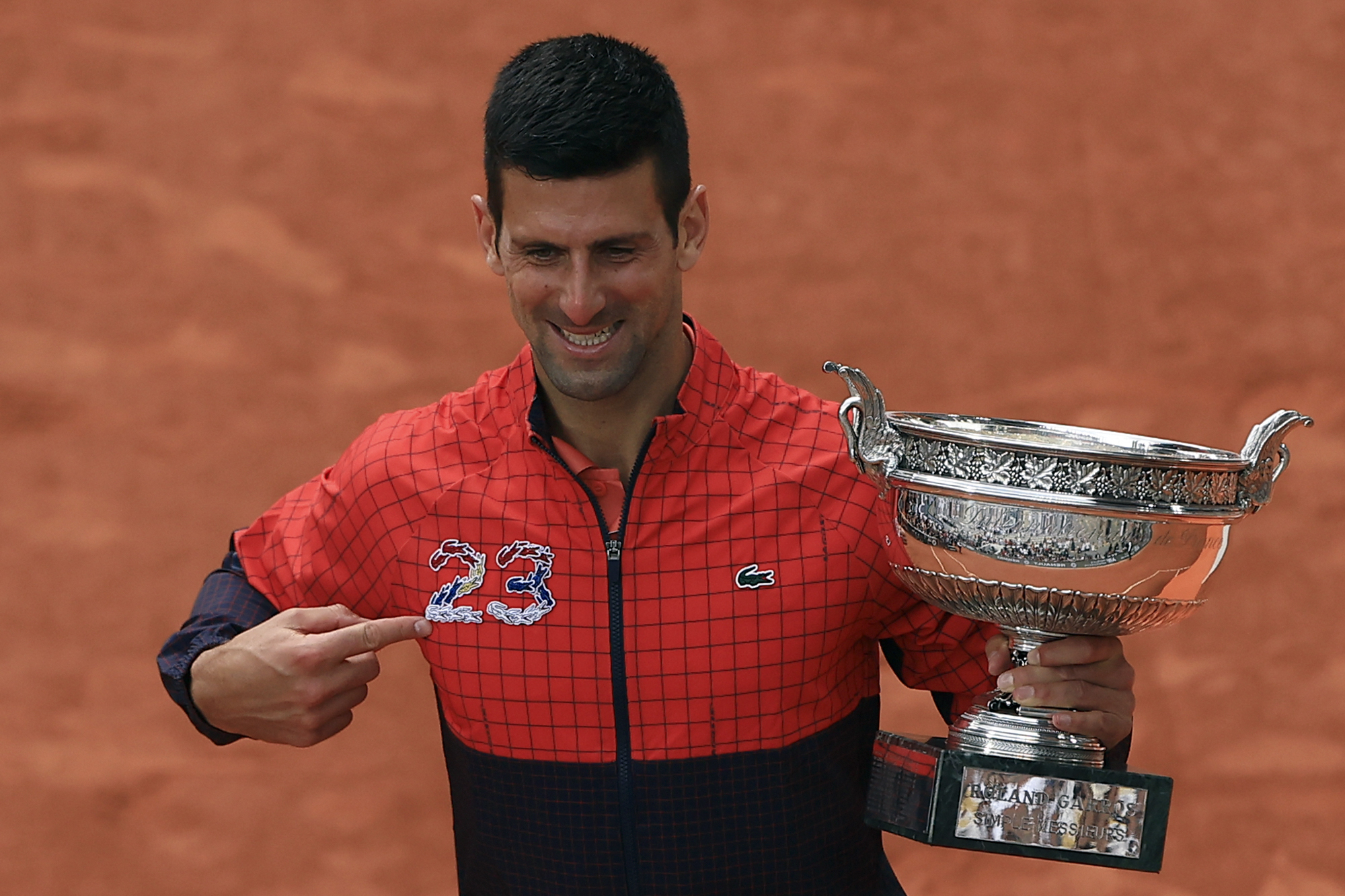 Novak Djokovic points to the number 23 on his jacket as he celebrates his French Open