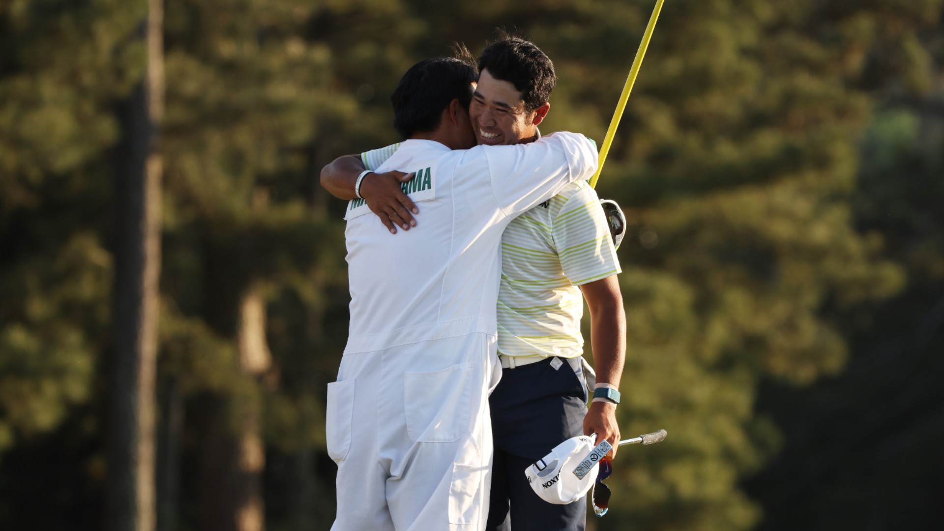 Hideki Matsuyama (R) shares an embrace with his caddie after winning The Masters