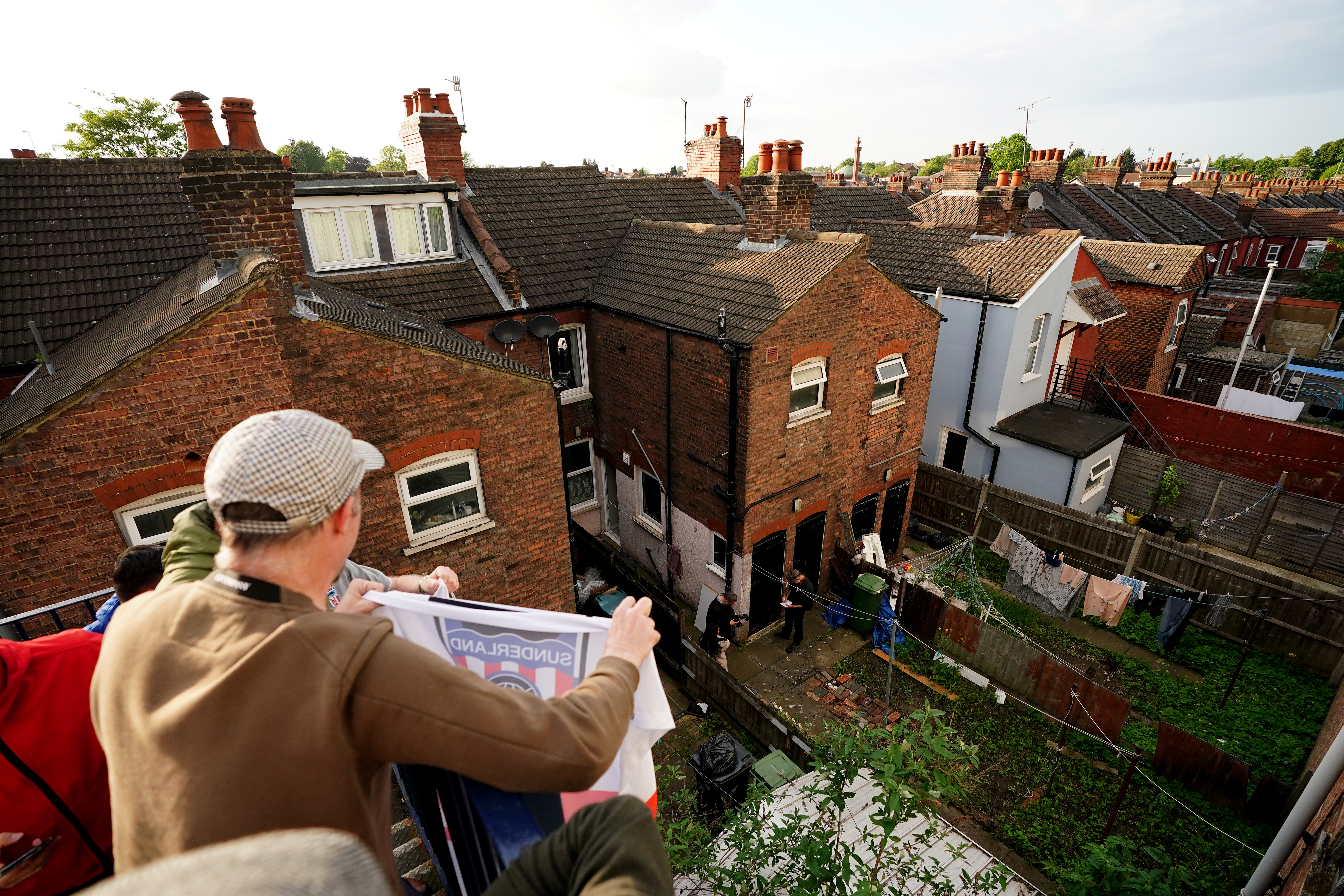 Sunderland fans gesture to residents in a garden next to Kenilworth Road
