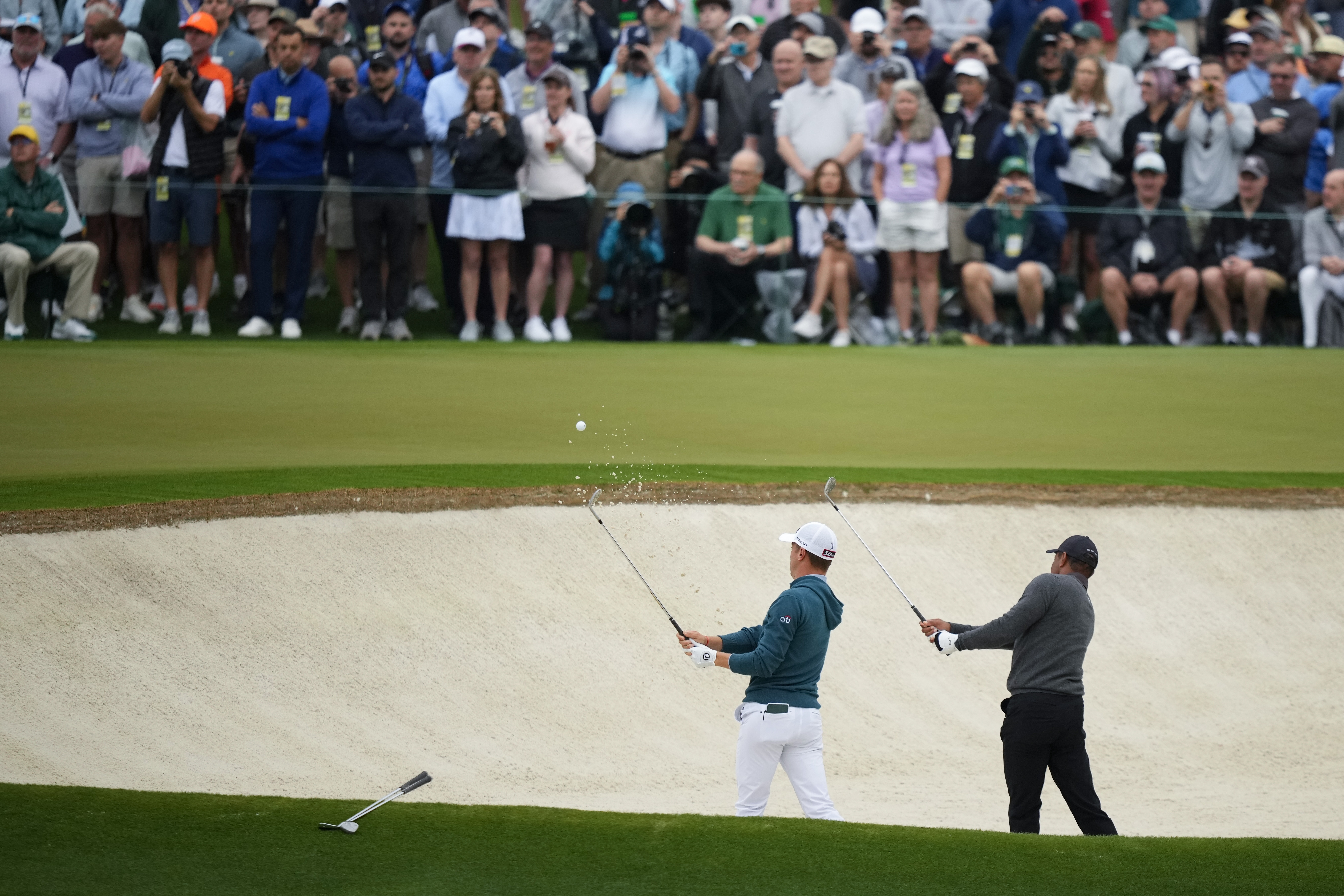 Justin Thomas, left, and Tiger Woods hit out of a bunker on the second hole in practice
