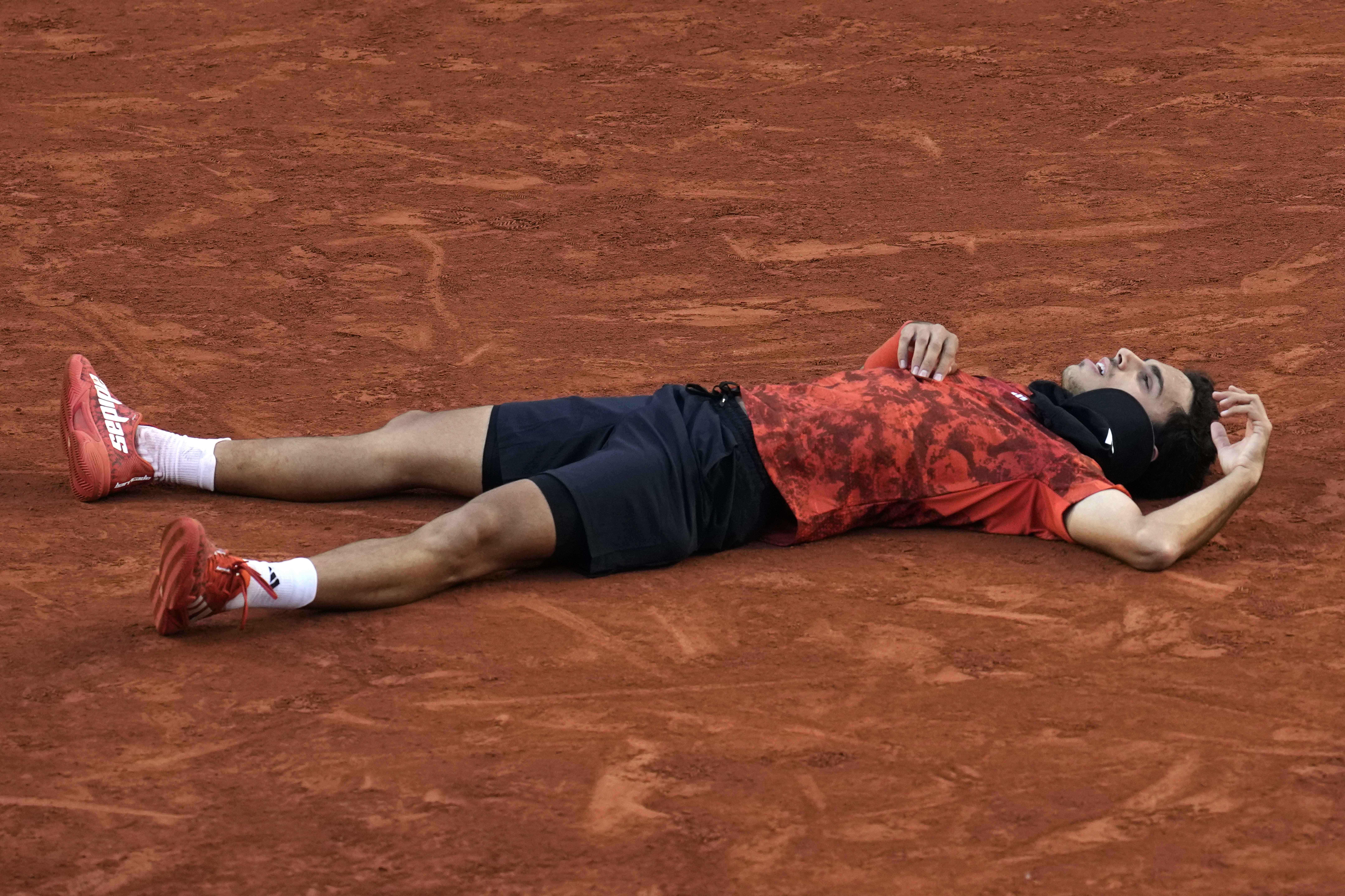 Francisco Cerundolo lies on the court after beating Taylor Fritz