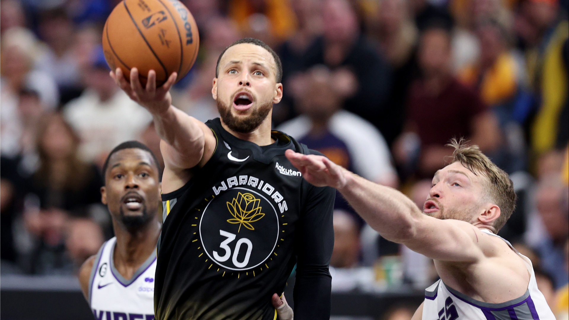 斯蒂芬·库里越过国王队后卫哈里森·巴恩斯和多曼塔斯·萨博尼斯进入篮筐