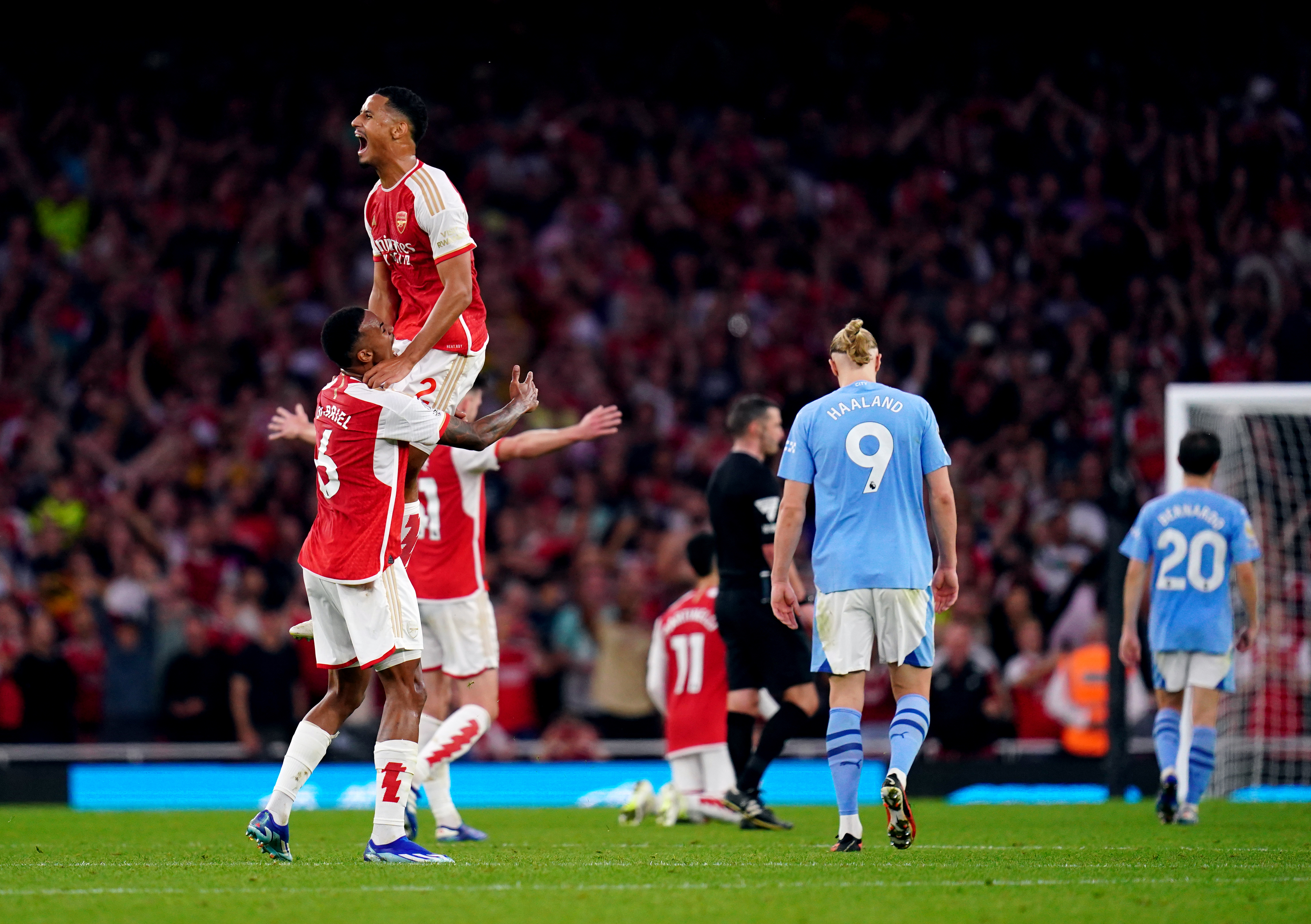 Arsenal’s William Saliba, top, and Gabriel celebrate victory as Manchester City players look dejected